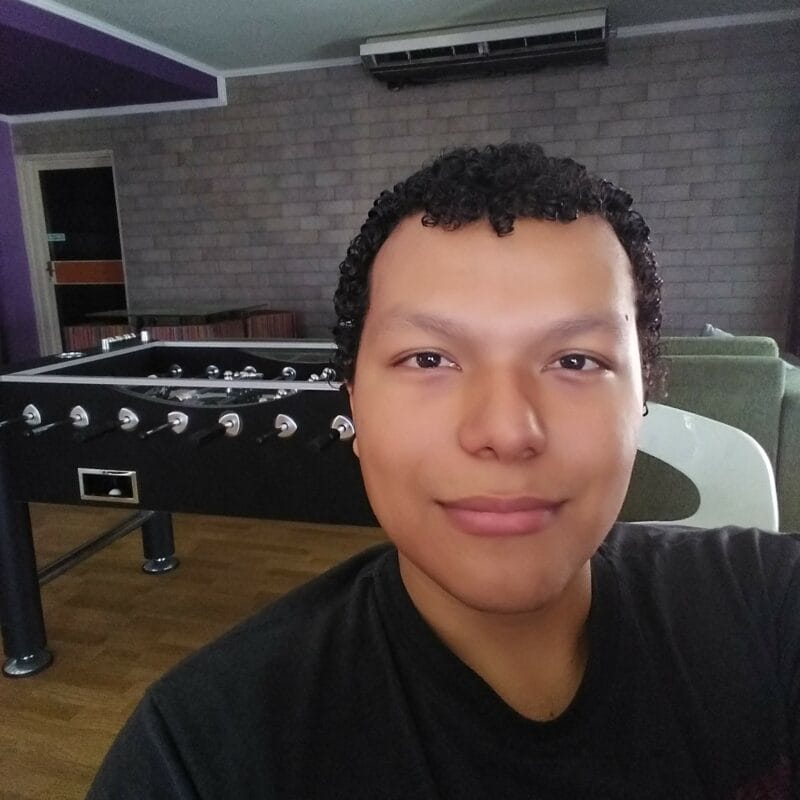 A selfie of Freddy wearing a black T-shirt. Behind him, a foosball table can be seen.