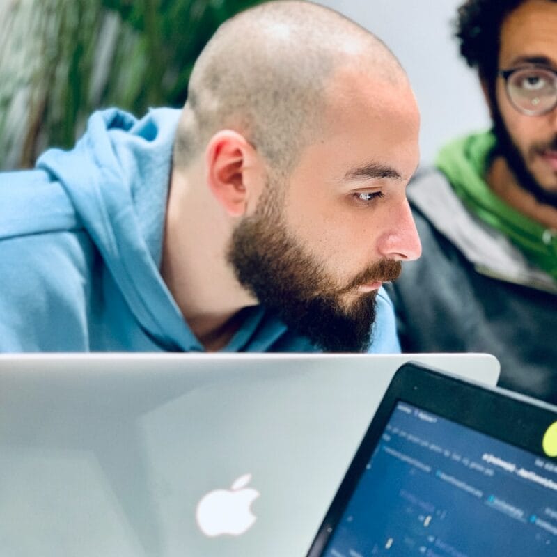 man in blue hoodie looking at macbook