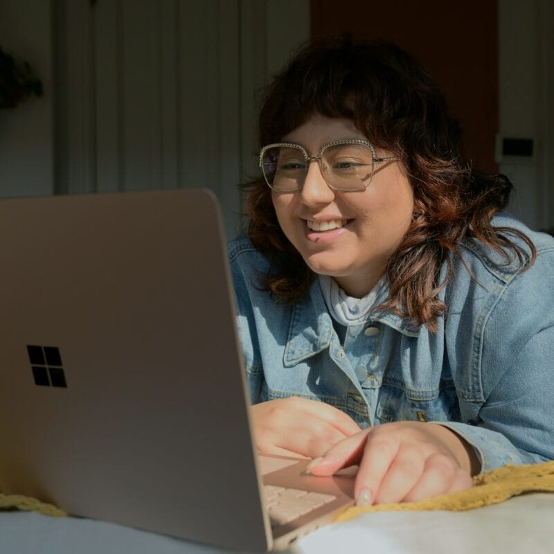 a woman in glasses is looking at a laptop