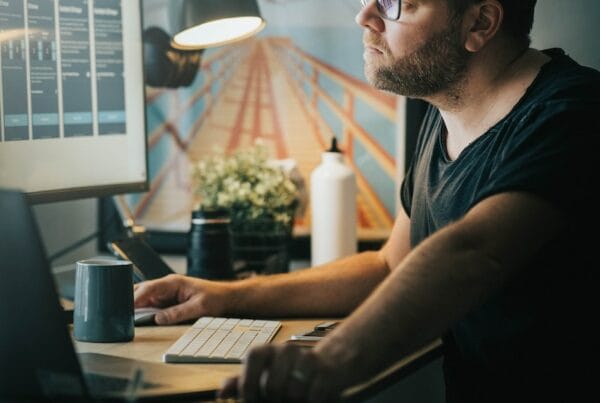 man in black crew neck t-shirt wearing black framed eyeglasses using computer