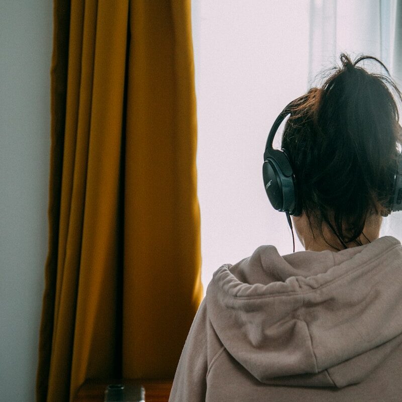 woman in gray shirt wearing black headphones