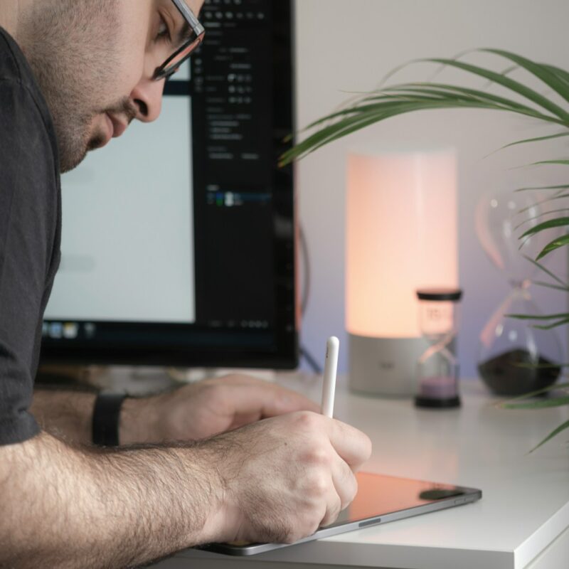 man in black t-shirt writing on white paper